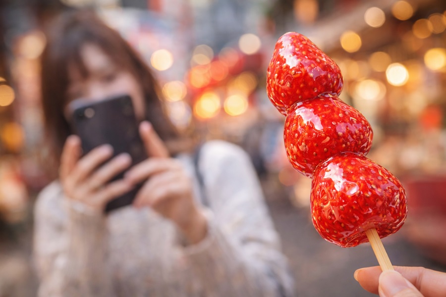 中華街でいちご飴を写す女性